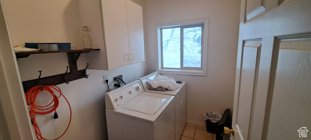 Laundry room with cabinets, hookup for a washing machine, washing machine and dryer, and light tile floors