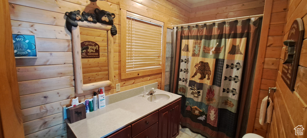 Bathroom featuring wood walls and vanity with extensive cabinet space