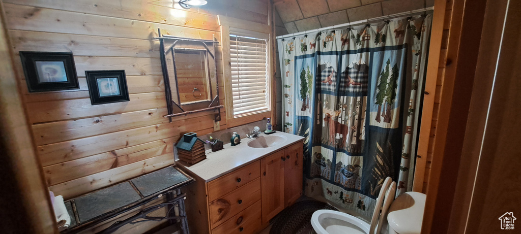 Bathroom featuring toilet, large vanity, and wood walls
