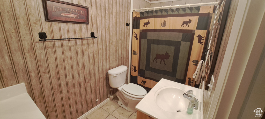 Bathroom with tile floors, wooden walls, vanity, and toilet
