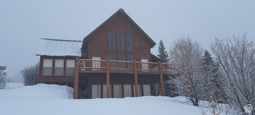 Snow covered back of property with a deck