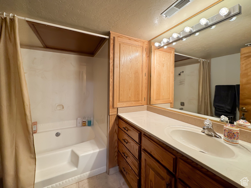 Bathroom with tile floors, a textured ceiling, and vanity with extensive cabinet space