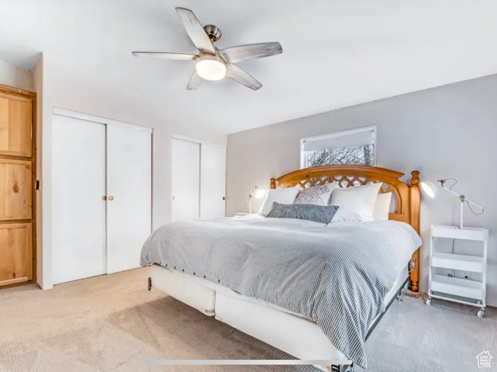 Carpeted bedroom with multiple closets and ceiling fan