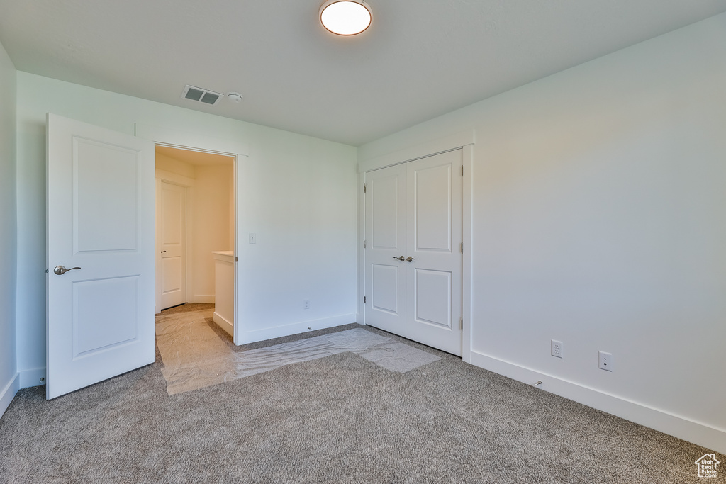 Unfurnished bedroom with a closet and light colored carpet