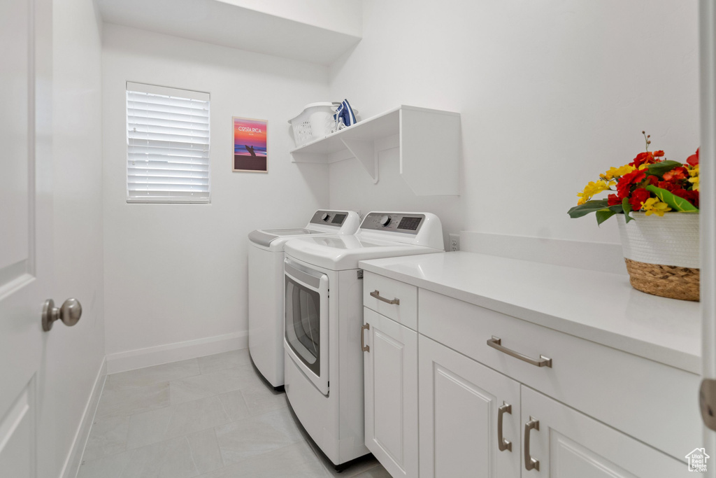 Laundry room with washer and dryer, light tile flooring, and cabinets