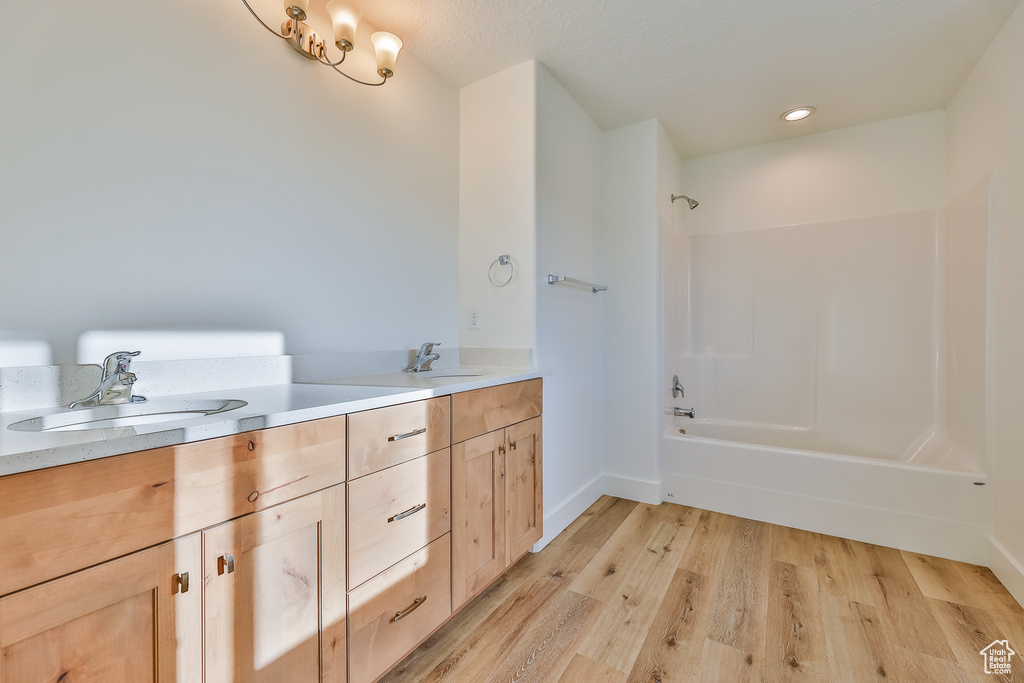 Bathroom featuring wood-type flooring, shower / washtub combination, and double sink vanity