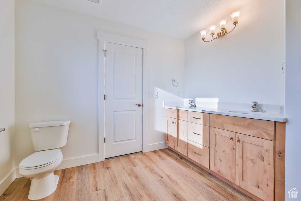 Bathroom with toilet, dual vanity, and wood-type flooring