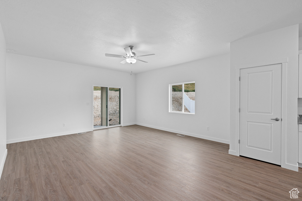 Unfurnished room featuring a wealth of natural light, ceiling fan, and dark hardwood / wood-style flooring