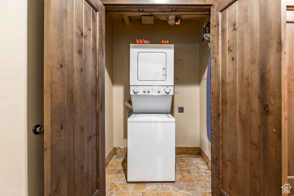 Laundry area with stacked washer and clothes dryer and light tile floors