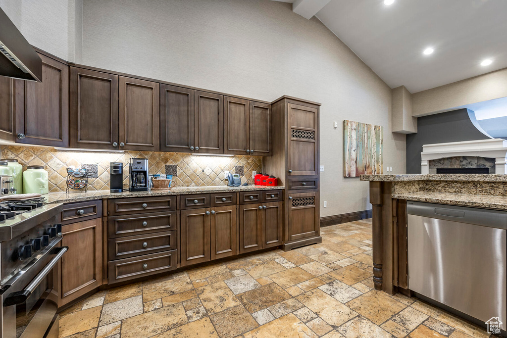 Kitchen featuring dark brown cabinetry, light stone countertops, stainless steel appliances, and wall chimney range hood