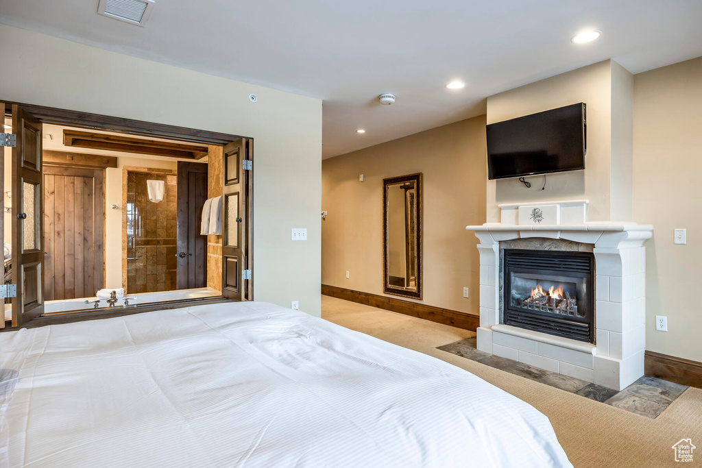 Bedroom with light carpet and a tile fireplace