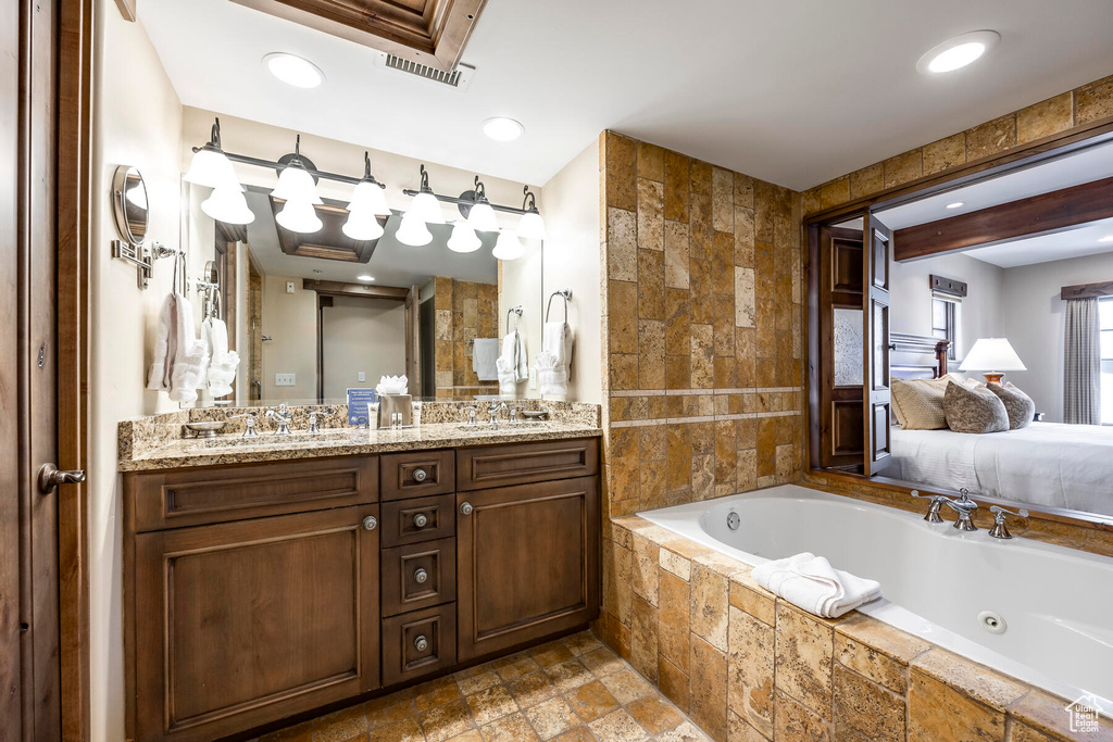 Bathroom with dual vanity, tiled tub, and tile flooring