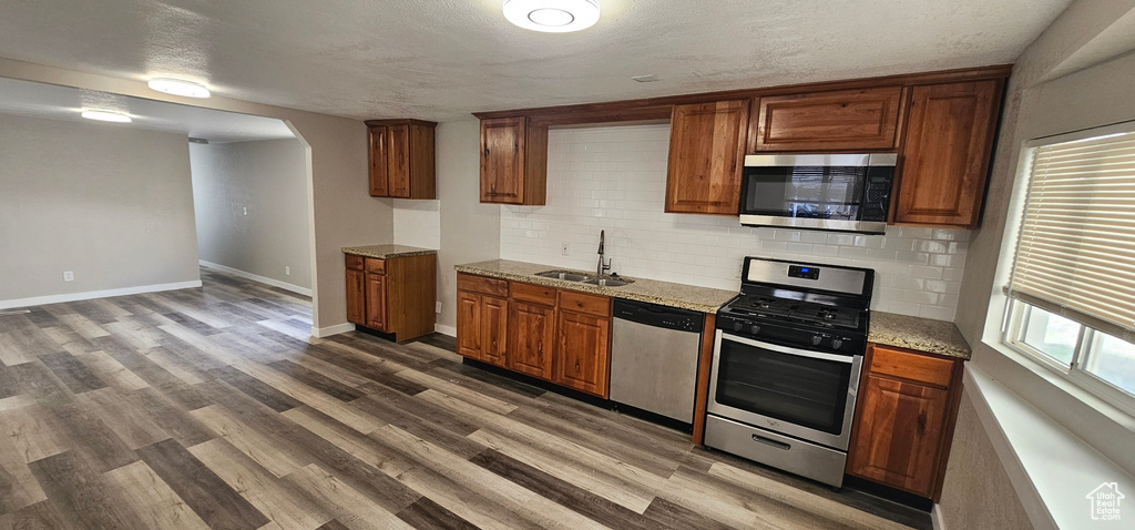 Kitchen featuring sink, backsplash, stainless steel appliances, and hardwood / wood-style floors