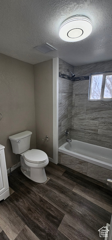 Full bathroom with vanity, toilet, a textured ceiling, and tiled shower / bath