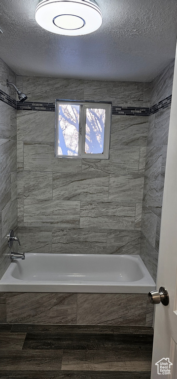 Bathroom featuring tiled shower / bath and a textured ceiling