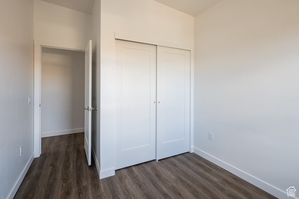 Unfurnished bedroom featuring a closet and dark wood-type flooring
