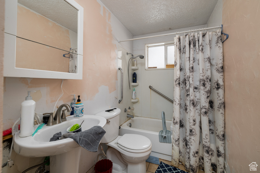 Full bathroom with shower / bathtub combination with curtain, a textured ceiling, sink, toilet, and tile floors