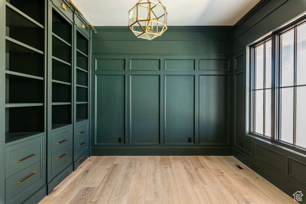 Spacious closet featuring light hardwood / wood-style flooring and a notable chandelier