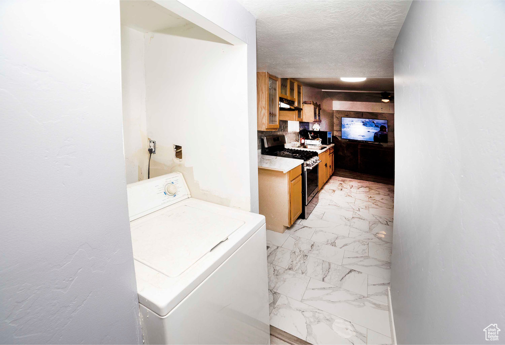 Laundry room with washer / dryer, a textured ceiling, and light tile floors