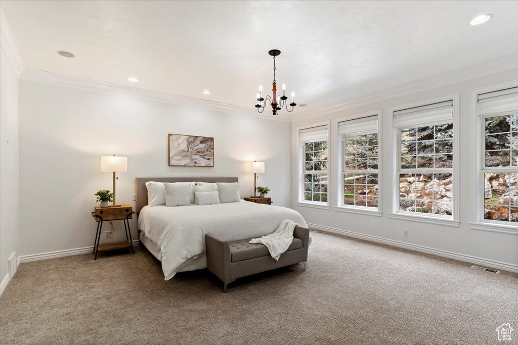 Carpeted bedroom featuring crown molding and a notable chandelier