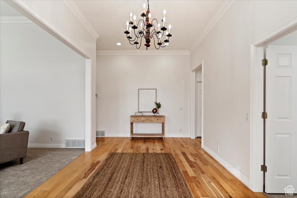 Interior space with light hardwood / wood-style flooring, ornamental molding, and a notable chandelier