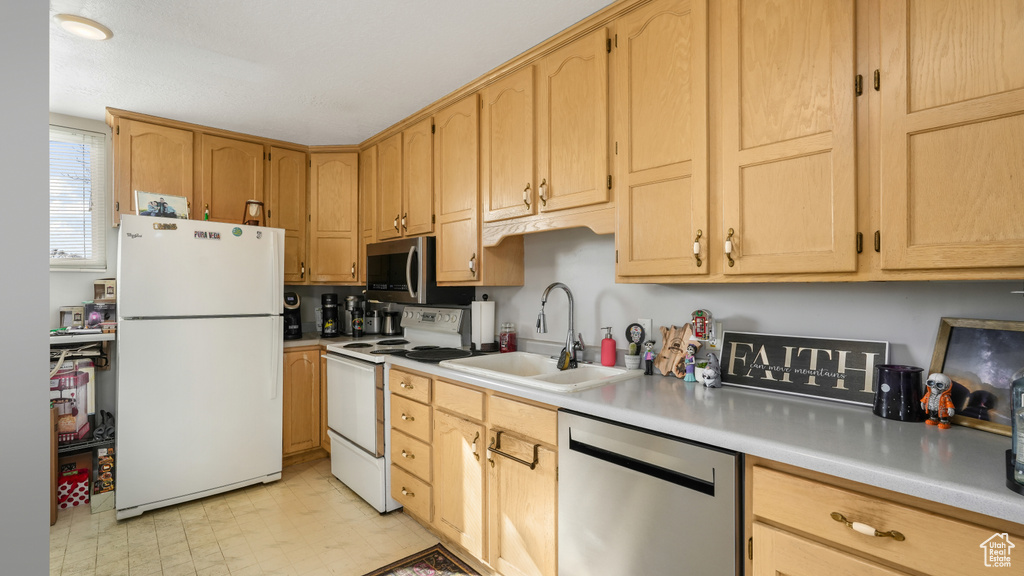 Kitchen featuring light brown cabinetry, sink, appliances with stainless steel finishes, and light tile floors