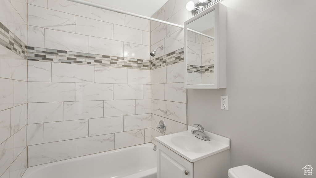 Full bathroom with tiled shower / bath combo, oversized vanity, and toilet