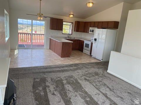 Kitchen featuring backsplash, white appliances, ceiling fan, lofted ceiling, and light carpet