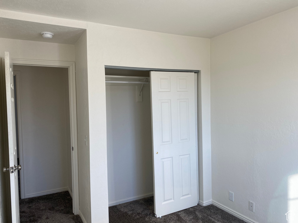 Unfurnished bedroom featuring dark carpet and a closet