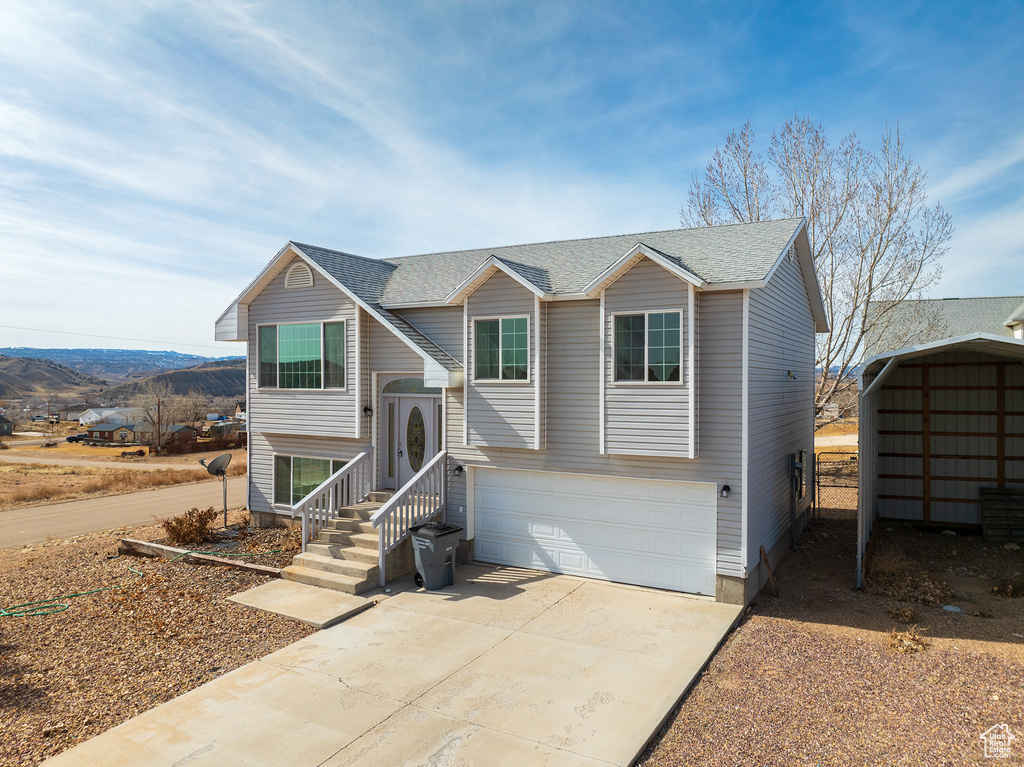 Raised ranch featuring a garage and a storage unit