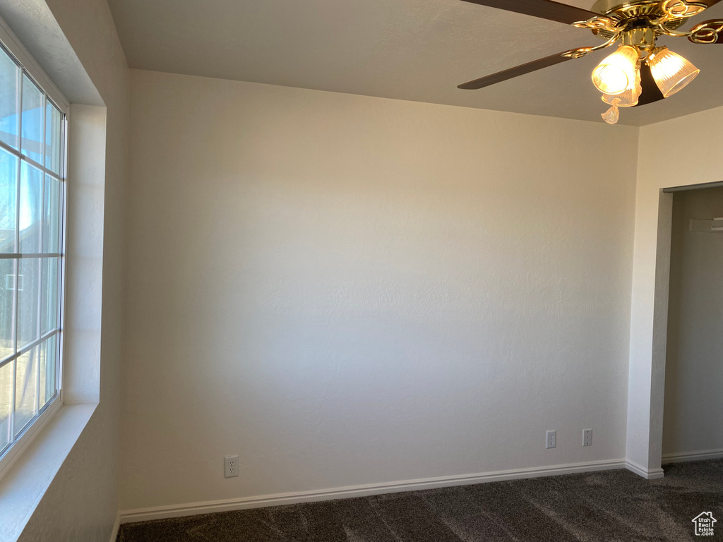 Spare room featuring dark carpet and ceiling fan