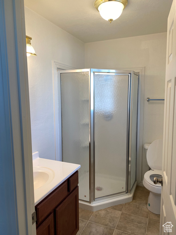 Bathroom featuring vanity, toilet, an enclosed shower, and tile floors