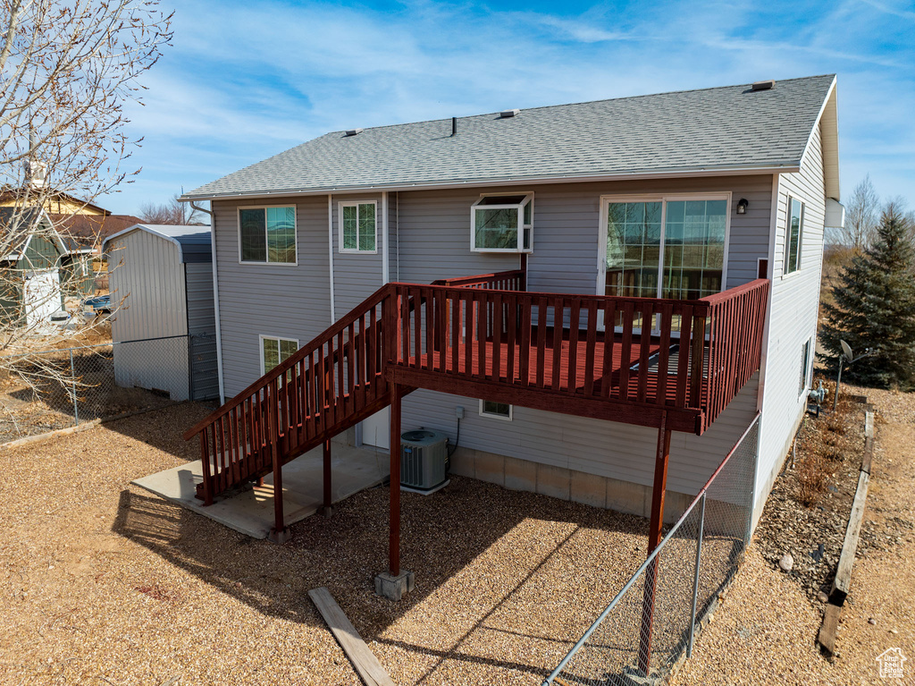 Back of property featuring a wooden deck and central AC