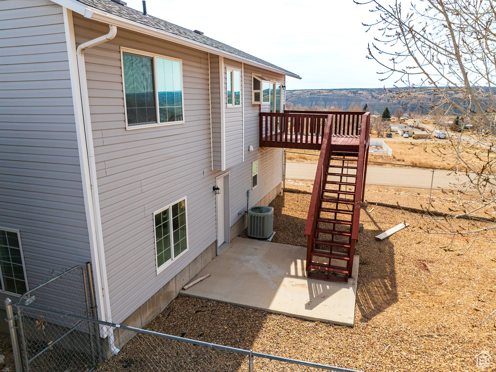 Rear view of property featuring a patio area, central air condition unit, and a wooden deck