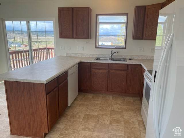 Kitchen with sink, white appliances, kitchen peninsula, and light tile floors