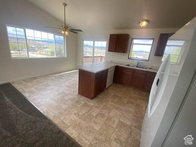 Kitchen featuring kitchen peninsula, ceiling fan, light tile flooring, and a wealth of natural light