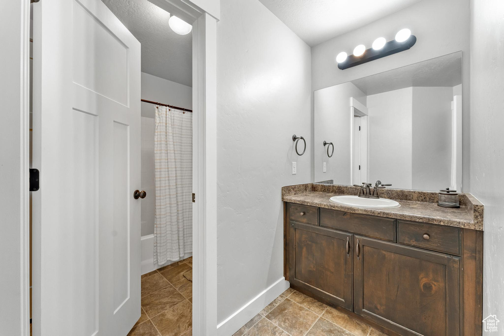 Bathroom with shower / bathtub combination with curtain, large vanity, and tile flooring