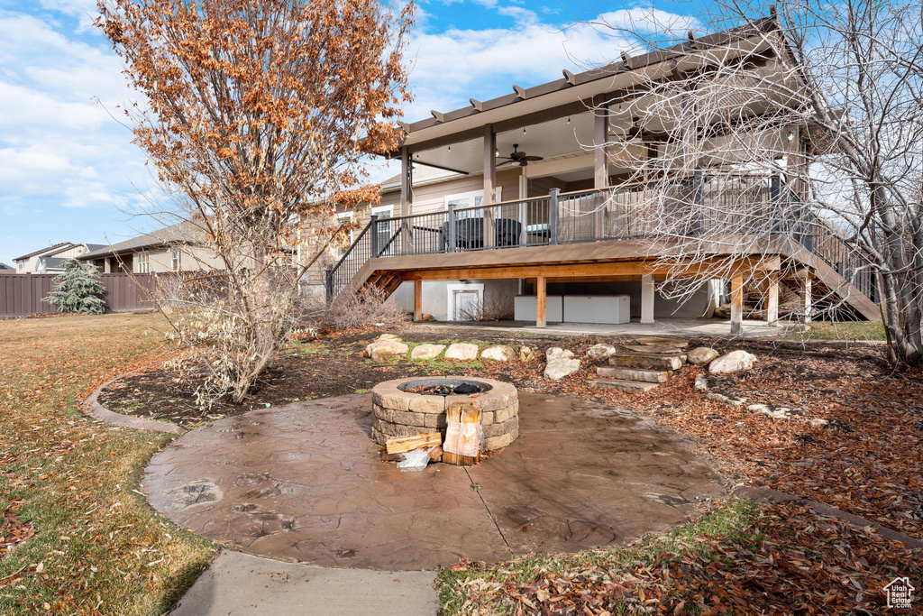 Back of property featuring a deck, ceiling fan, an outdoor fire pit, and a patio