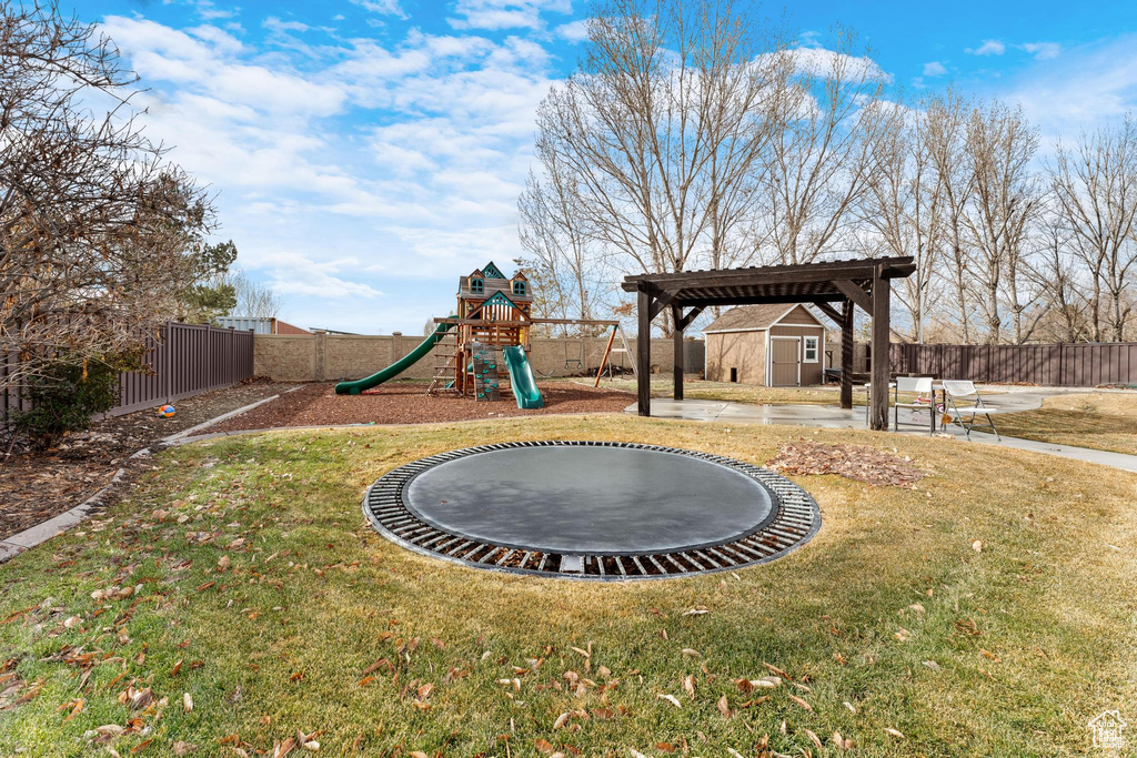 View of yard with a shed, a playground, and a trampoline
