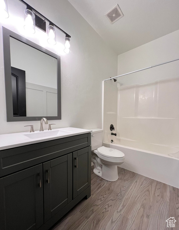 Full bathroom with hardwood / wood-style flooring, tub / shower combination, vanity, and toilet