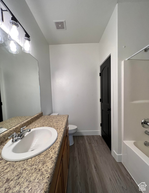 Full bathroom with toilet,  shower combination, oversized vanity, and wood-type flooring