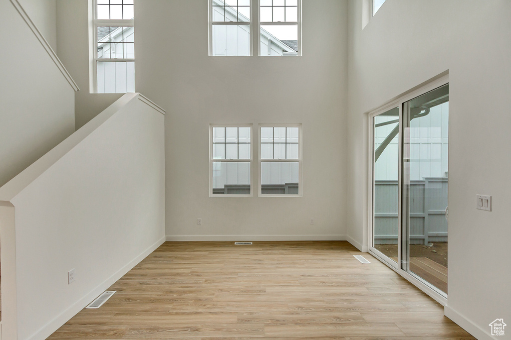 Empty room featuring a wealth of natural light, light hardwood / wood-style floors, and a towering ceiling