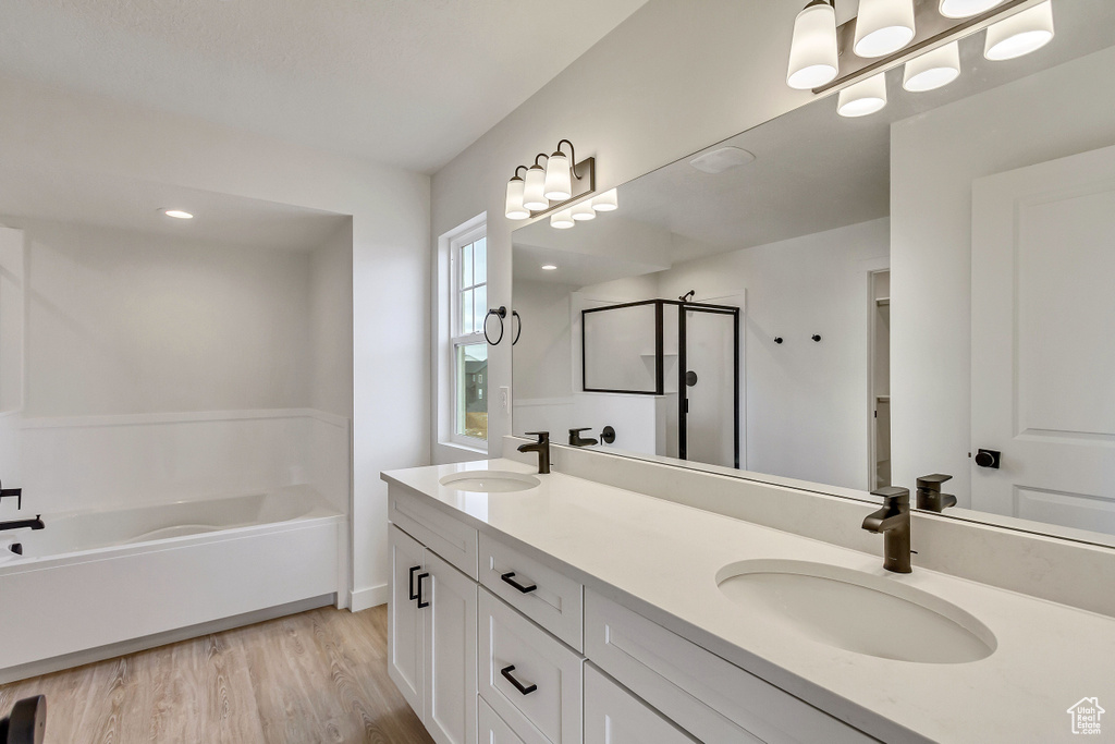 Bathroom featuring hardwood / wood-style flooring, dual bowl vanity, and plus walk in shower