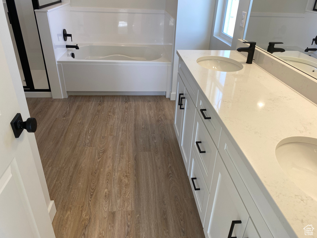 Bathroom featuring double vanity, hardwood / wood-style flooring, and a bath