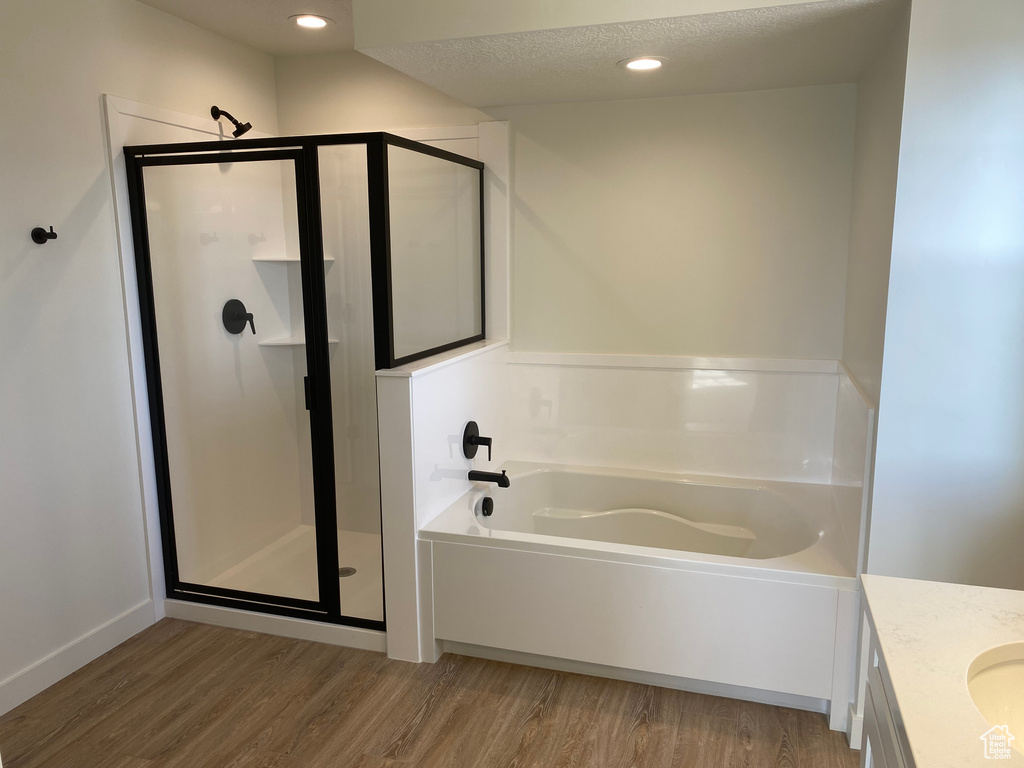 Bathroom featuring hardwood / wood-style floors, vanity, separate shower and tub, and a textured ceiling
