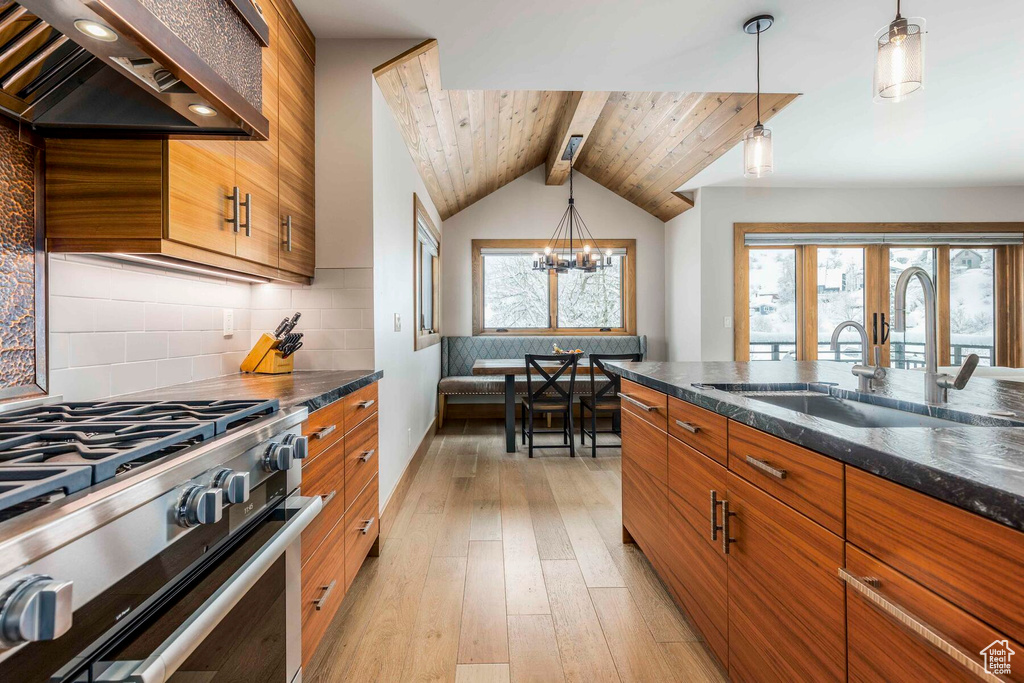 Kitchen featuring backsplash, light hardwood / wood-style floors, high end range, wall chimney range hood, and wooden ceiling