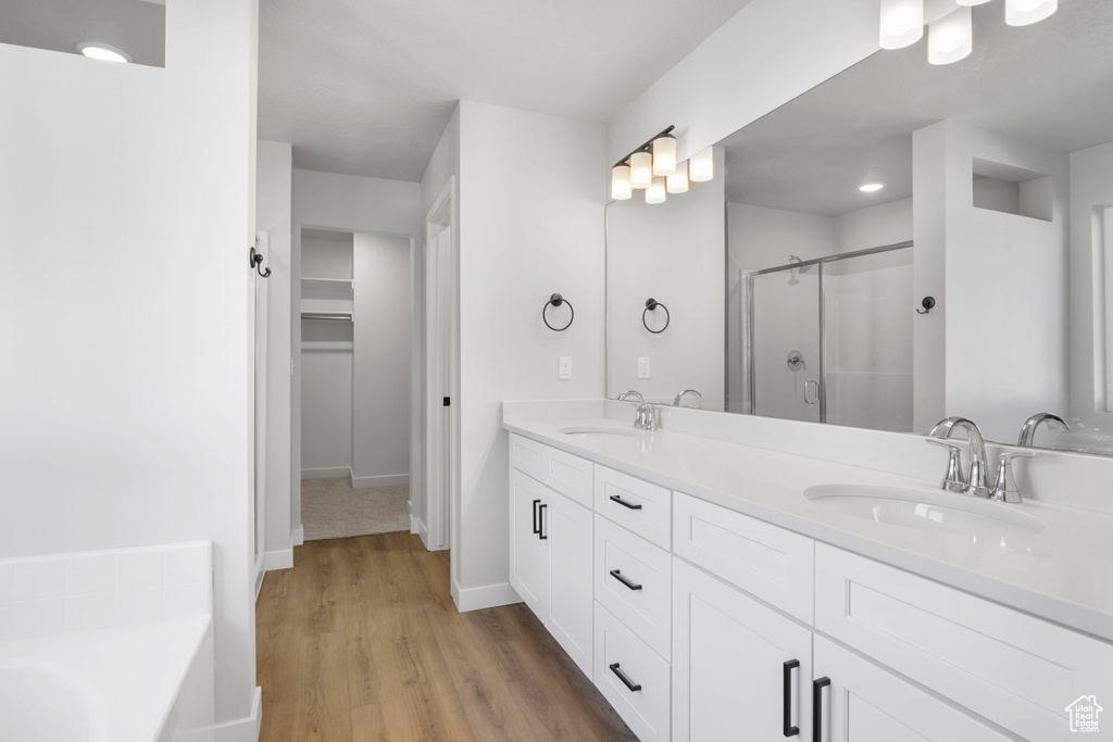 Bathroom with hardwood / wood-style floors, independent shower and bath, and double sink vanity