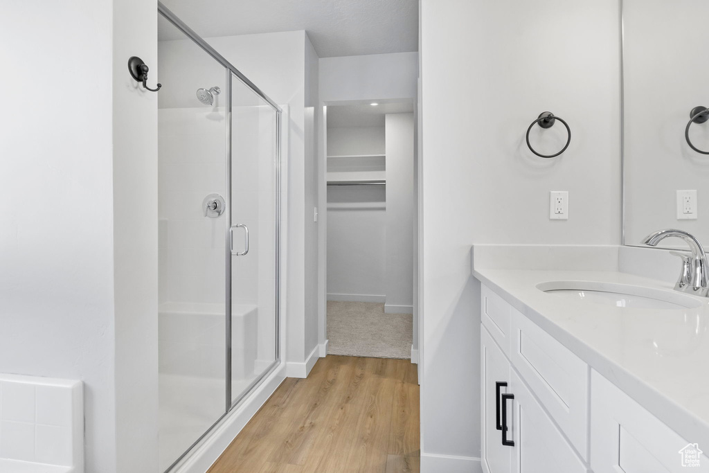 Bathroom with a shower with shower door, wood-type flooring, and vanity