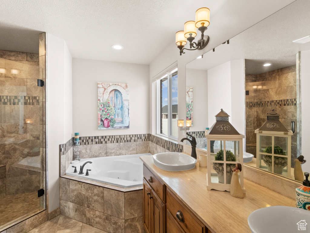 Bathroom featuring shower with separate bathtub, double sink, a chandelier, large vanity, and tile flooring