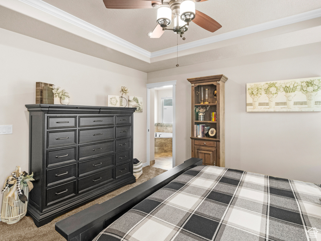 Bedroom with crown molding, ensuite bathroom, ceiling fan, and a raised ceiling